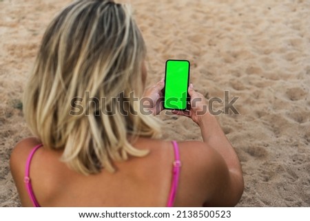 Girl on the beach holding a smartphone with Green screen. Chroma Key.