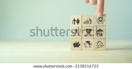 Insurance and stages of life concept.  Hand puts wooden cube with assurance icon standing on finance, education, real estate and property, health, child, family and pension planing icon, smart banner Royalty-Free Stock Photo #2138516723