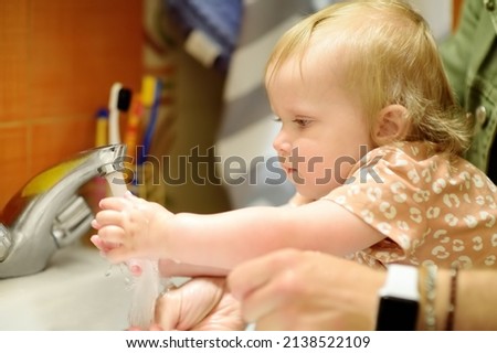 Cute baby and her dad washing their hands with soap in bathroom together. Hygiene for little child. Father's involvement in raising children. Happy parenthood. Royalty-Free Stock Photo #2138522109
