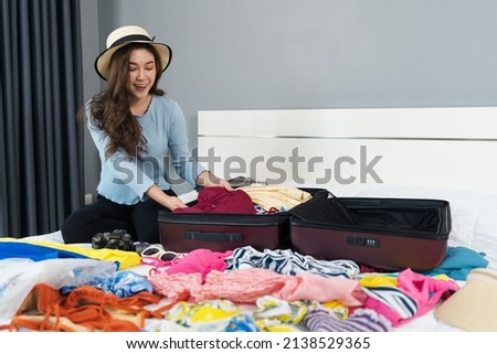 young woman preparing and packing clothes into suitcase on bed at home, holiday travel concept