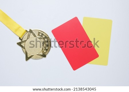 A picture of gold medal with red and yellow card. Sports disqualification concept.