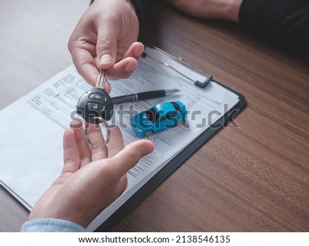 Concept car rental. Close up view Hand of agent giving car key to customer after signed rental contract form.