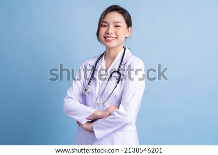 Young Asian female doctor standing on blue background