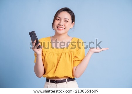 Young Asian girl using smartphone on blue background
