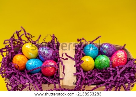Easter composition from a basket and colored eggs prepared for the holiday on a yellow background