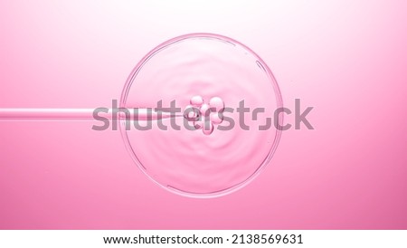 Different sized air bubbles come out from chemical dropper and float on the surface of transparent liquid in petri dish bursting on pink background | Abstract cosmetics formulation concept