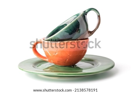 Empty cups for drinks and a green plate on a white background. The concept of handmade kitchen utensils. Close-up