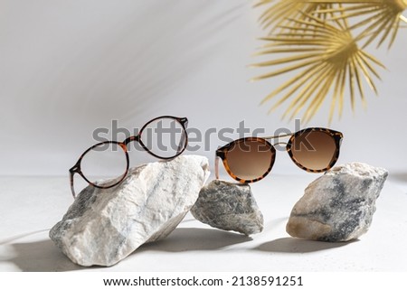 Trendy sunglasses of different design and eyeglasses on gray background with golden palm leaf. Copy space. Sunglasses and spectacles sale concept. Optic shop promotion banner. Eyewear fashion Royalty-Free Stock Photo #2138591251
