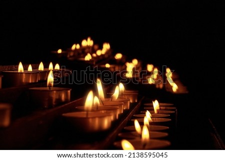 Close-up of votive candles, tea lights, in a dark Christian church. Italy, Europe
