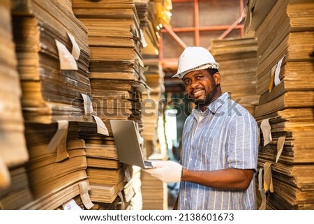Happy male factory manager using digital tablet in warehouse while standing  shelf looking at camera.Products and corrugated cardboard. Factory for the manufacture.small business factory concept.