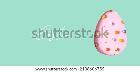 Happy Easter text with Easter egg cut out of paper and chocolate mini eggs. Creative Easter holiday greeting card banner format