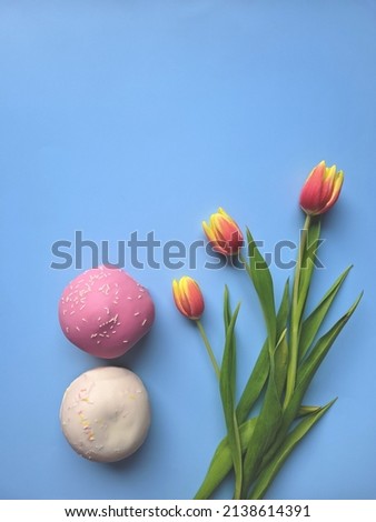 Morning with yellow, red tulips and sweet donuts on blue background. Top view, copy space, mockup. Flat lay. Food and drinks. Spring holidays. 