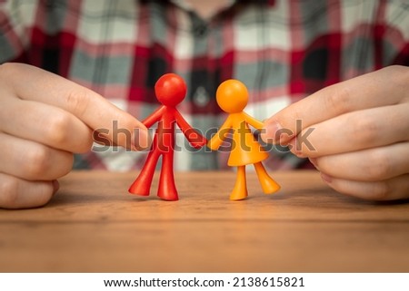 Figurines of parents in human hands. Concept of family values and fatherhood background 