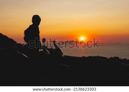 Silhouette of Biker man and his adventure motorcycle. Enjoying perfect sunset view. Freedom concept. Travel and tourism. Italy