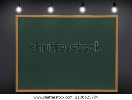 Glowing light bulbs and green chalkboard hanging on grey wall