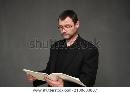 Business man in glasses and a black jacket looks into a folder