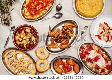 Spanish restaurant tapas set with scrambled eggs with Iberian ham, fried chicken wings, meatballs with potatoes, Andalusian squid, potato omelette and patatas bravas