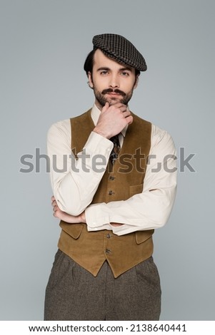 pensive man with mustache and retro clothing looking at camera isolated on grey