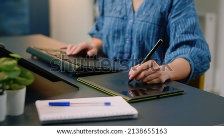 Close up of hands using graphic tablet with stylus and keyboard on computer for pictures retouching at studio. Photography artist working with technology and editing equipment.