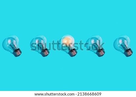close-up of an incandescent lamp and one glowing lamp on an isolated blue background. The concept of energy efficiency. Flat lay. Concept ecology, saving planet Earth, idea, energy saving, economy.
