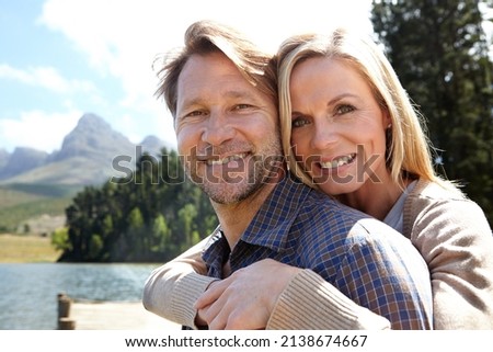 Im holding on to this one. Portrait of an affectionate mature couple sitting on a pier out on a lake.