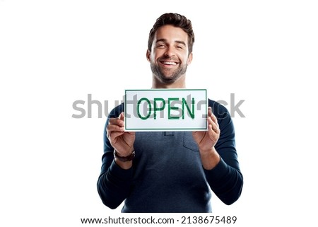 Happy to have you as a customer. Studio portrait of a handsome young man holding an open sign against a white background.