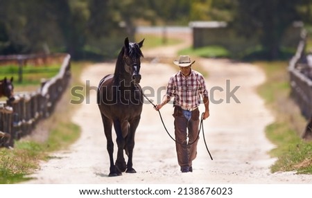 Lets go for a talk. Shot of a cowboy leading his horse by the reins. Royalty-Free Stock Photo #2138676023