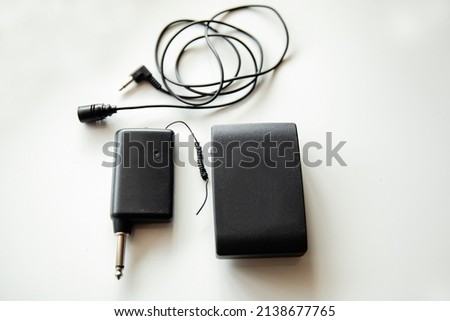 Radio microphone buttonhole on a light background. Receiver and transmitter. Equipment for reporting and videography.