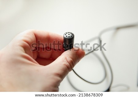 Radio microphone buttonhole on a light background.  Equipment for reporting and videography.