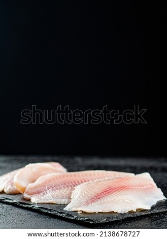 Uncooked fish fillet on the table. On a black background. High quality photo
