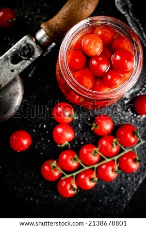 Pickled tomatoes in a jar on a stone board. On a black background. High quality photo