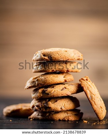 Pile of homemade cookies with pieces of milk chocolate on the table. On a wooden background. High quality photo