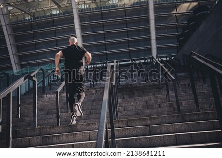 Photo of sportive healthy retired man black sportswear running stairs enjoying cross fit outside urban city street.