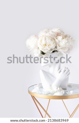 Fresh bunch of white peonies in vase in shape of womens face on light background. Trendy Ceramic Vase of human head, Handmade Modern Statue Art Flower Vase. Card Concept, copy space for text Royalty-Free Stock Photo #2138683969