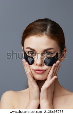 pretty woman eye patches on face bare shoulders skin care isolated background