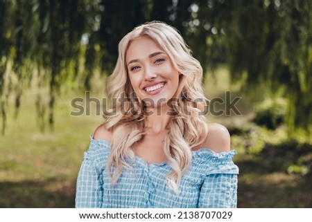 Portrait of attractive cheerful wavy-haired girl enjoying springtime weekend pastime on fresh air village outdoors.