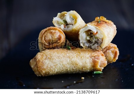 Fresh stack of egg rolls. Top eggroll is broken open to see the ingredients inside. Selective focus with blurred foreground and background. 
