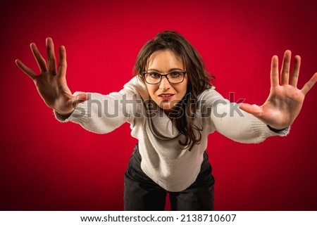 The pretty girl, emotional on a red-cherry background, put her hands forward and said away, restrain, do not let go. Concept failure, confrontation, protection, harassment at work, women's rights.