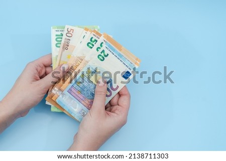 Woman's hands counting stack of euro banknotes on blue background. Money. Business. Finance