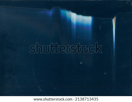 Distressed filmstrip. Blue glowing flecks. Dark dusty overlay. Royalty-Free Stock Photo #2138713435
