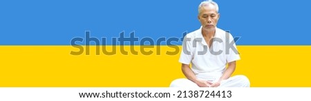 An elderly man meditating on a Ukrainian flag in prayer background. The idea of standing with Ukraine in war with Russia