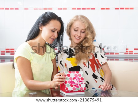 Two young women looking at the gift box