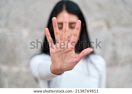 woman raises her hand to say enough is enough. Campaign to stop violence against women. Latina woman with her hand covering her face Royalty-Free Stock Photo #2138769811