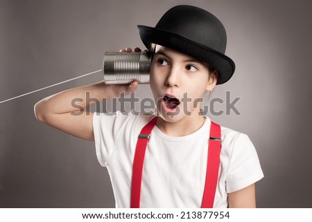 little girl using a can as telephone on a gray background