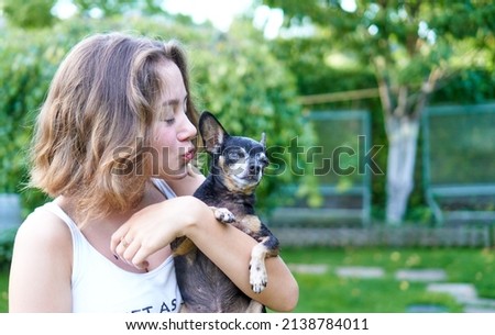 Young girl kissing little dog in the summer garden