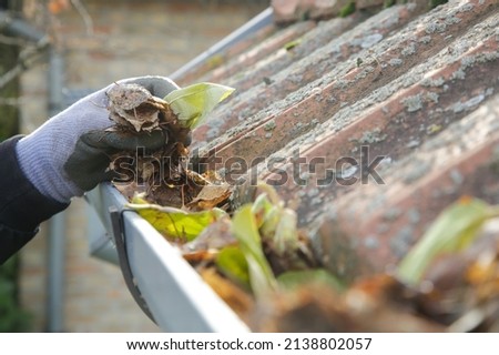Cleaning the gutter from autumn leaves before winter season. Roof gutter cleaning process.	 Royalty-Free Stock Photo #2138802057
