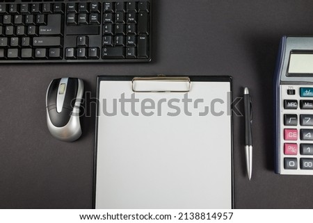 Top view photo of office clipboard with keyboard, mouse, pen and calculator on black background with copy space