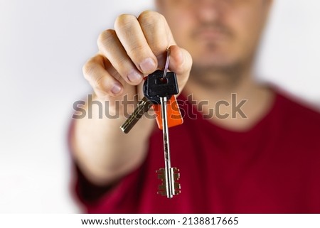 The hand gives the keys to the house, a white photo, a blurry background.