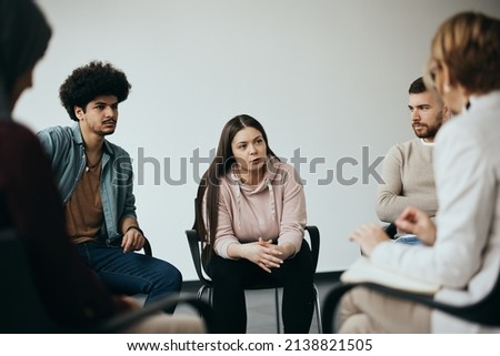 Young woman sharing her problems with a therapist and attenders of group therapy at community center. Royalty-Free Stock Photo #2138821505