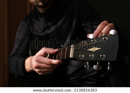 male musician tuning the strings on the guitar Royalty-Free Stock Photo #2138826383